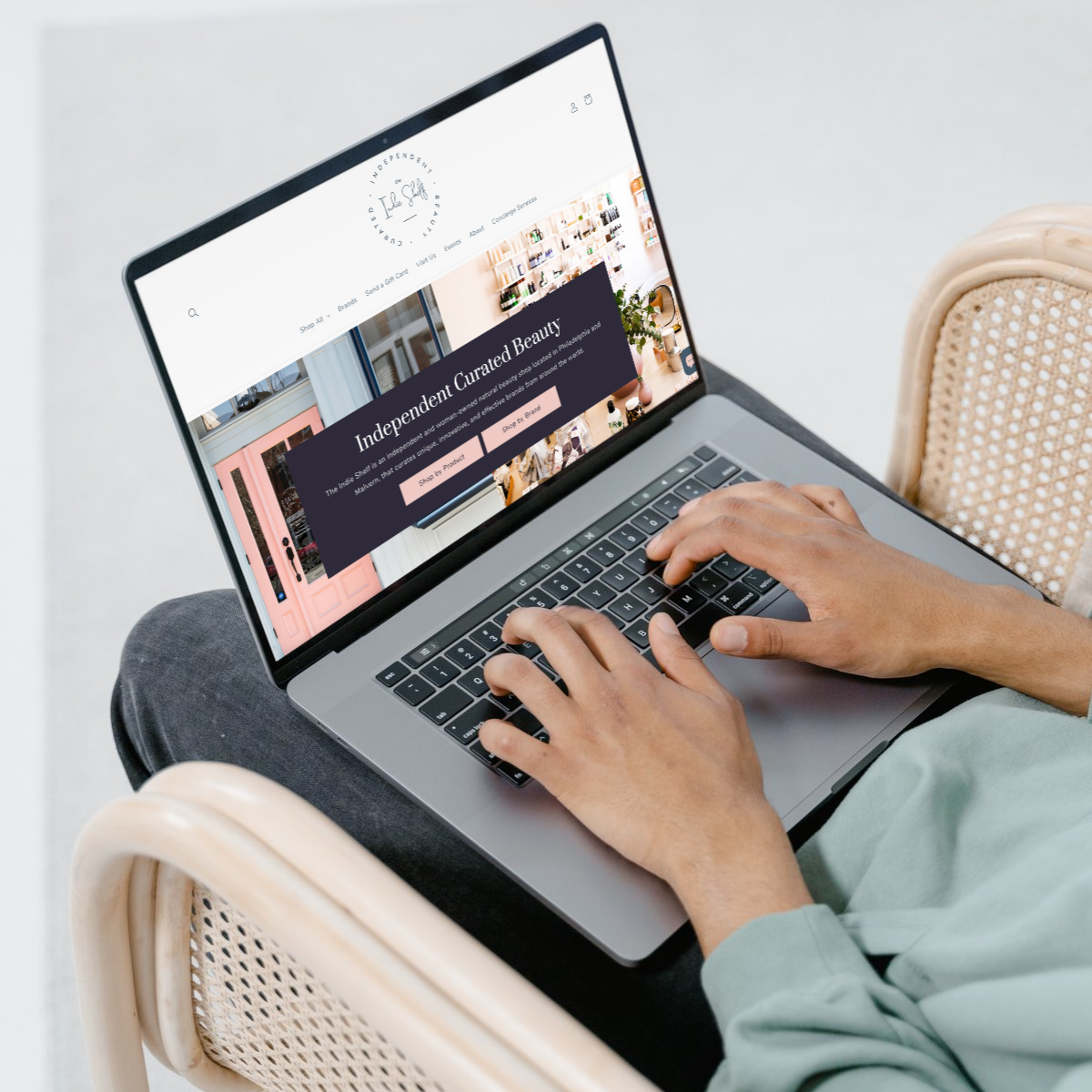Person browsing an independent beauty e-commerce website on a laptop, sitting in a modern woven chair. Optimized online store design with a clean layout and clear call-to-action buttons. Ideal for showcasing user-friendly e-commerce website design and email marketing growth strategies for small and midsize businesses.