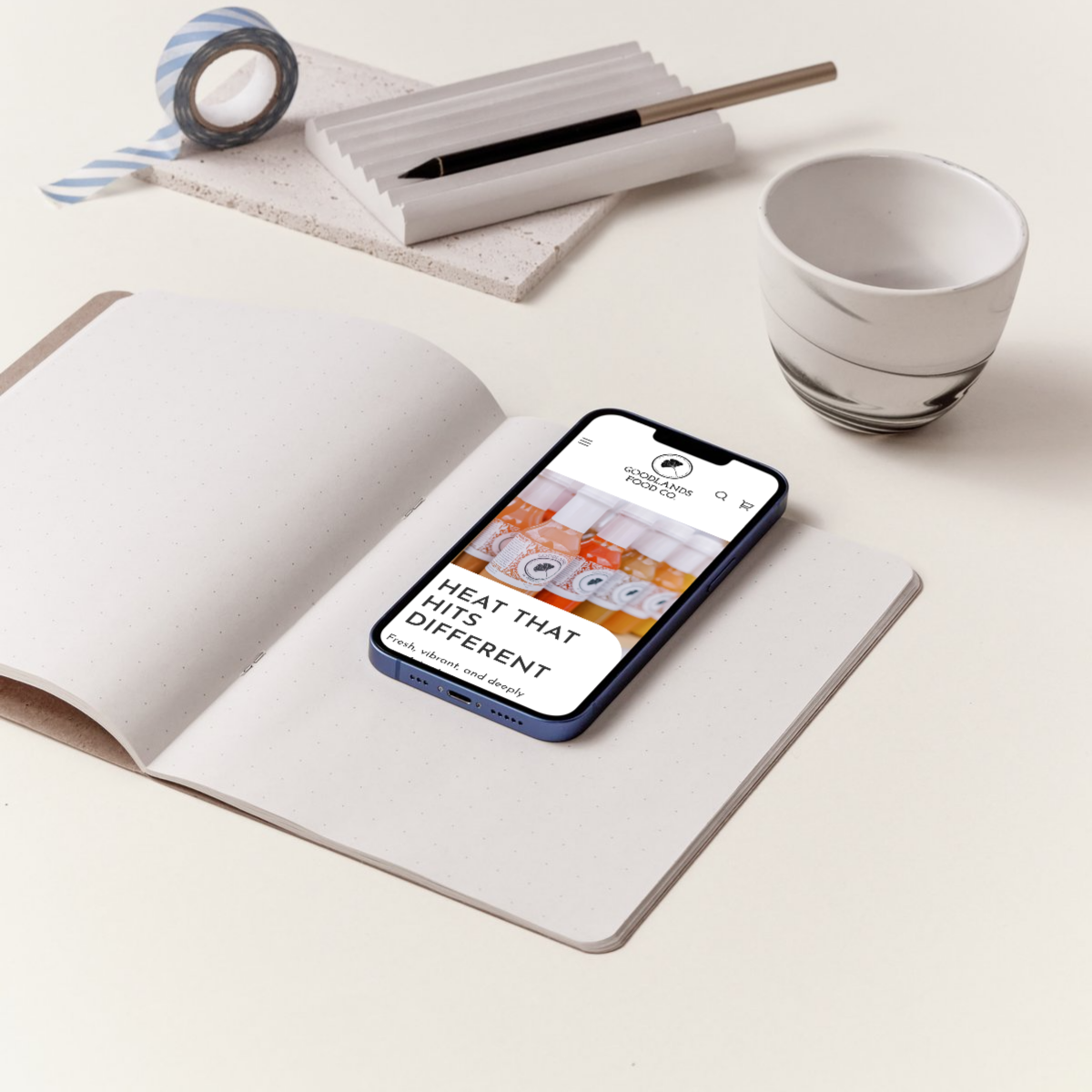 Custom Shopify mobile website for hot sauce brand shown on iPhone, on a notebook with minimalist desk setup – showcasing mobile-first ecommerce design by the Next Chapter Designs team.