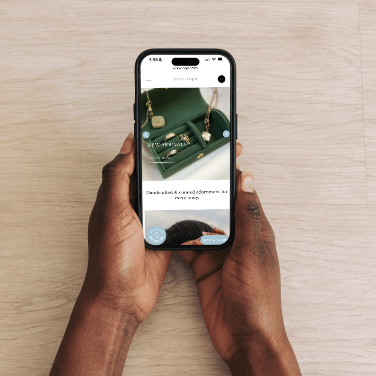 Person browsing a mobile-friendly jewelry ecommerce website featuring handcrafted and curated adornments. The screen displays a green jewelry box with elegant gold pieces, emphasizing a premium online shopping experience. A great example of ecommerce UX/UI design for small brands.