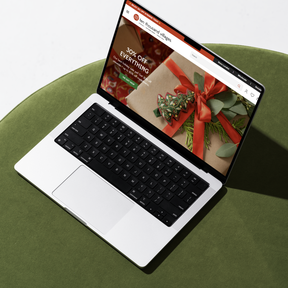 MacBook displaying an ecommerce website for Ten Thousand Villages with a holiday sale promotion. Designed by Next Chapter Designs, specializing in ecommerce web design and email marketing for small and midsize businesses looking to grow their revenue and customer base.
